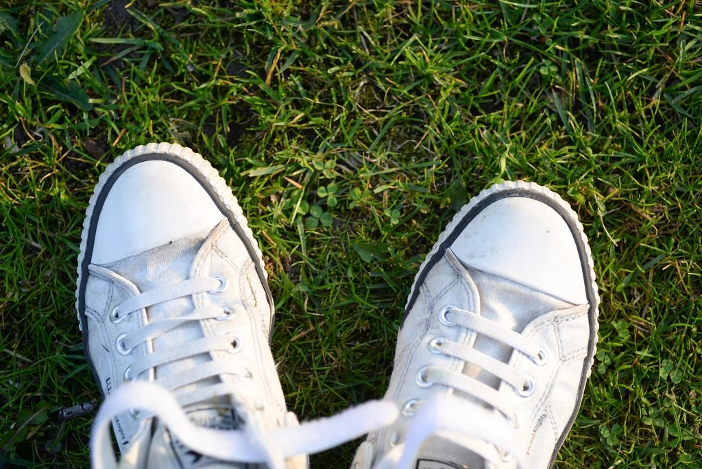 White low-top school sneakers on grass, lightly dirty from wear